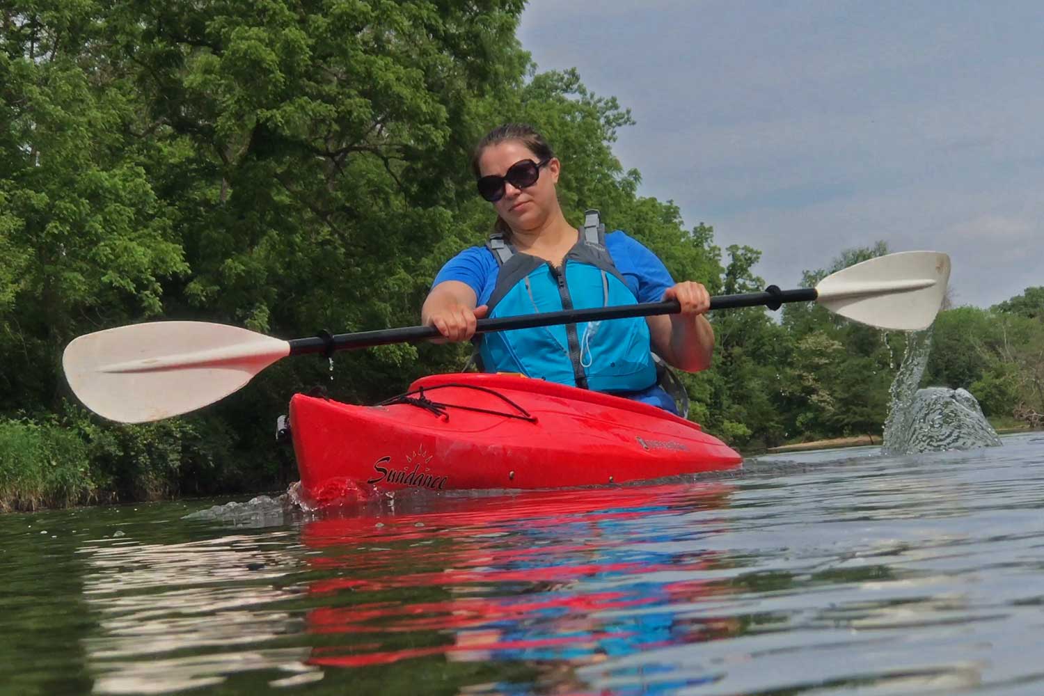 Person in a kayak with the tree line in the background.