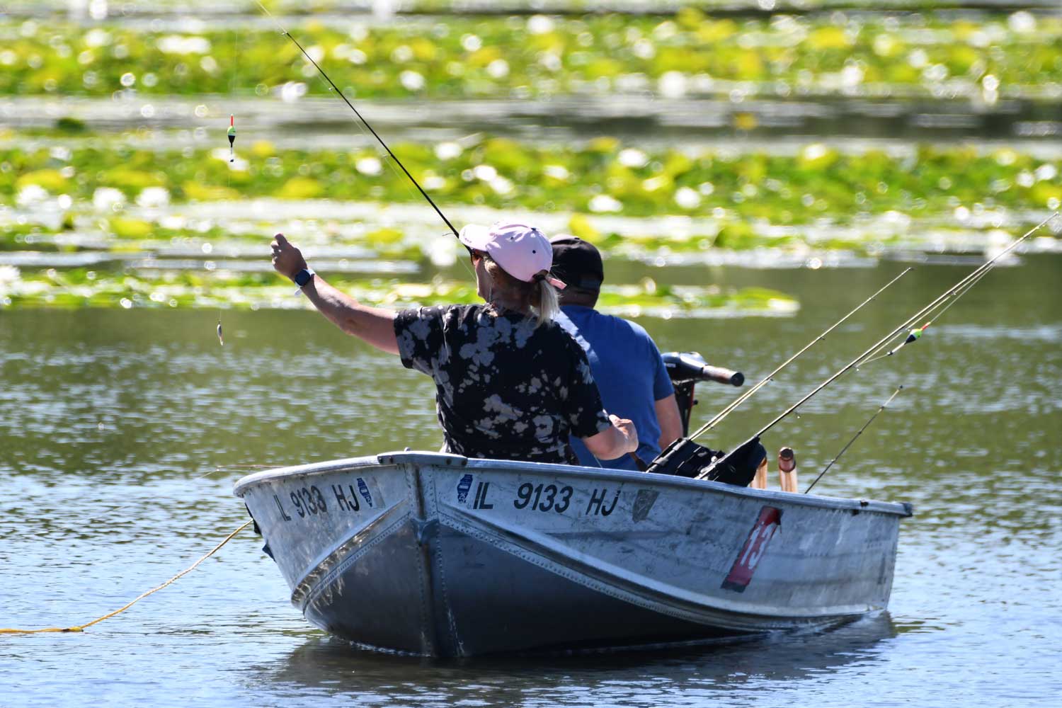 Two people sitting down in a boat while fishing.