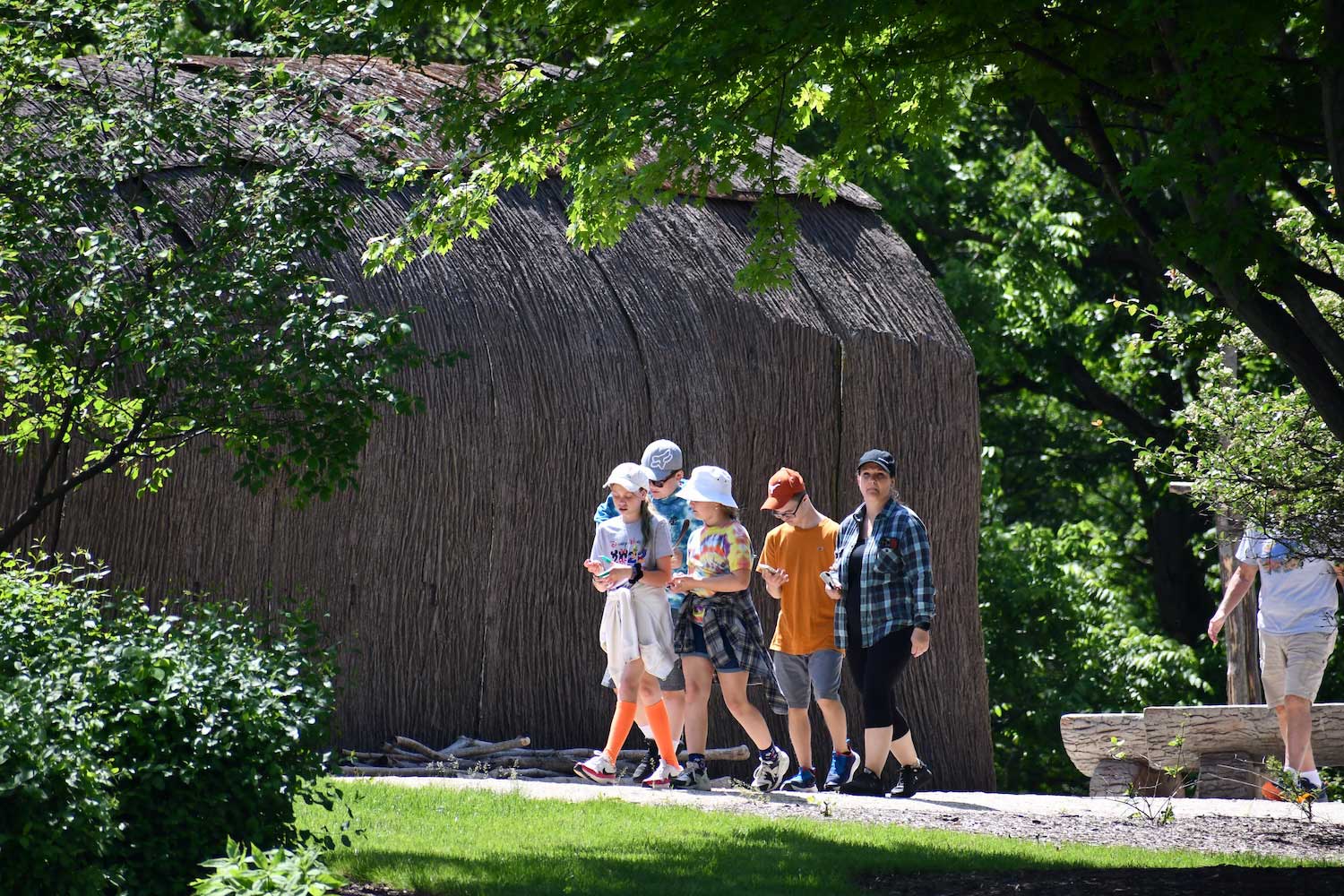 A group of people walking by a longhouse.