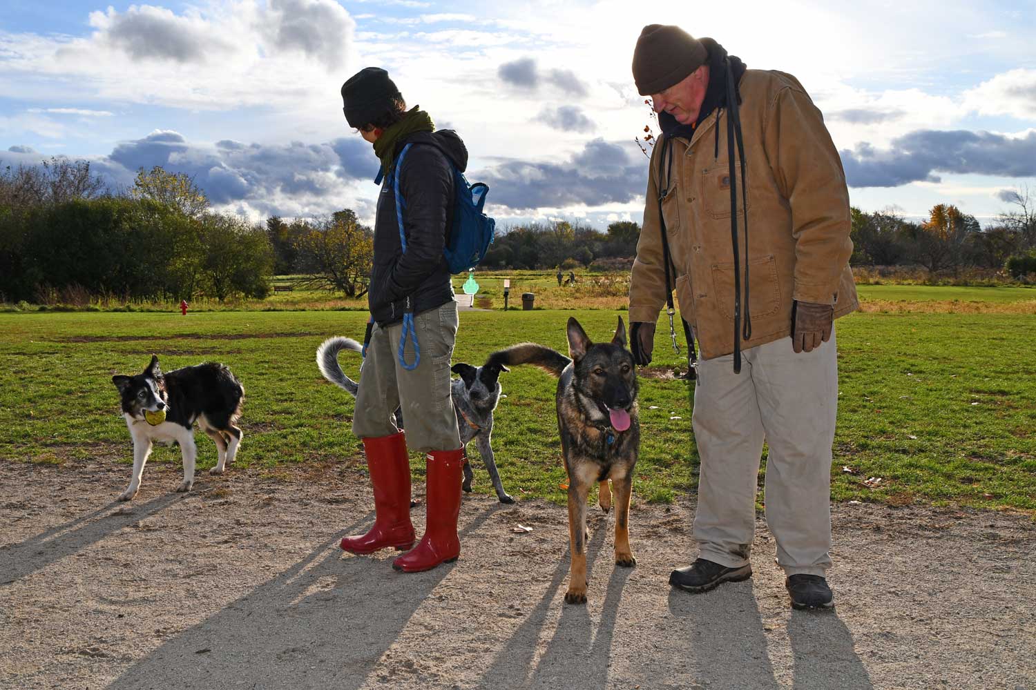 Two dog park visitors with their dogs.