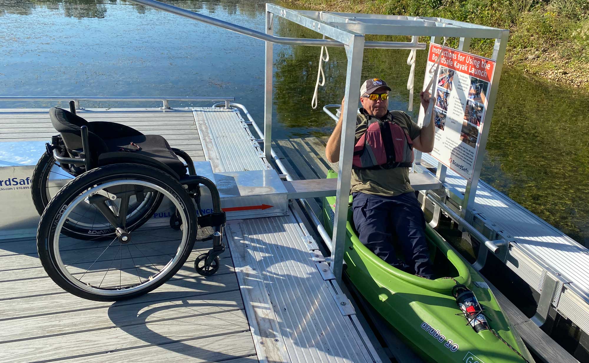 A man gets into a kayak by using an accessible launch.