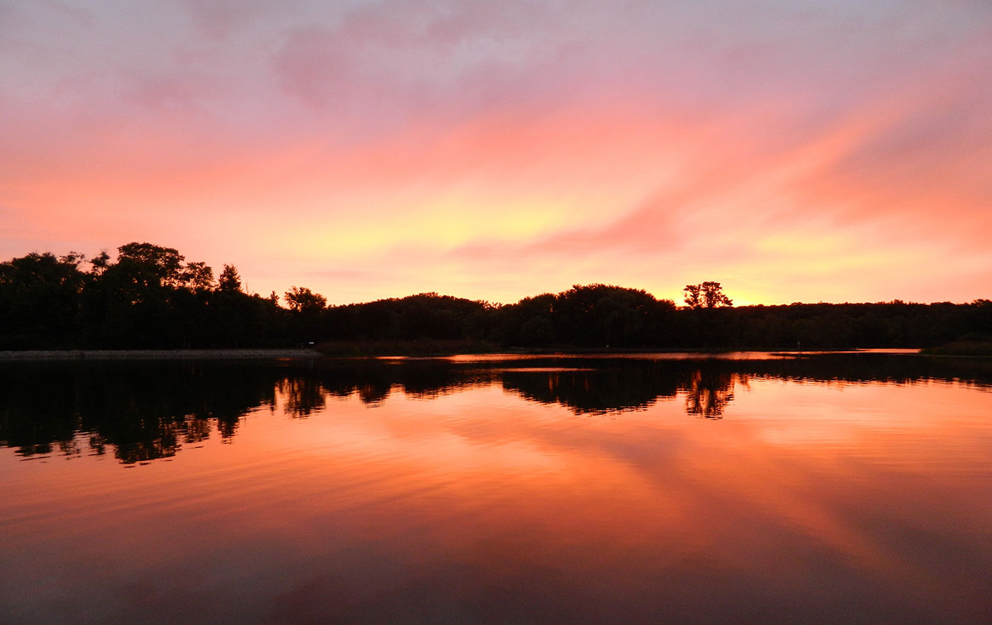 A colorful sunset over water with the sky in shades of pink and orange.