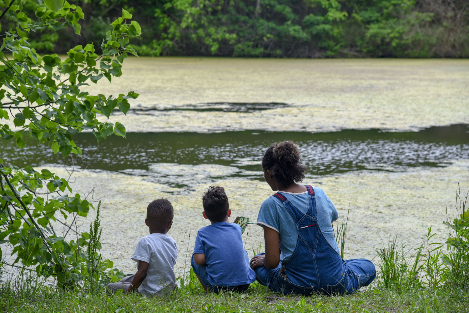 Kids sitting on ground by a pond
