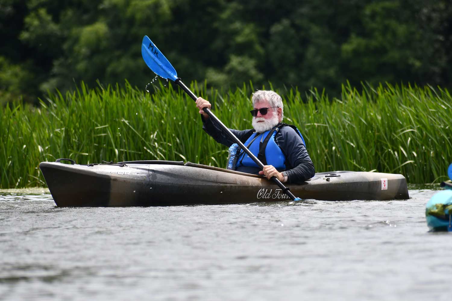 Person in a kayak with tall grasses in the background.