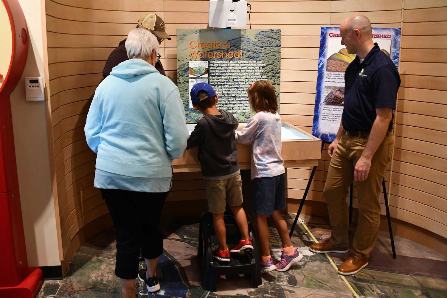 Two children looking at an interactive exhibit while three adults look on.