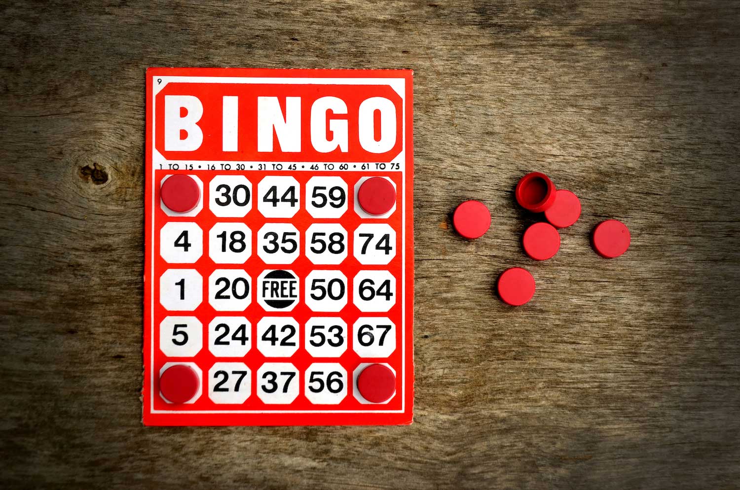 A bingo card with a pile of red bingo markings next to it.