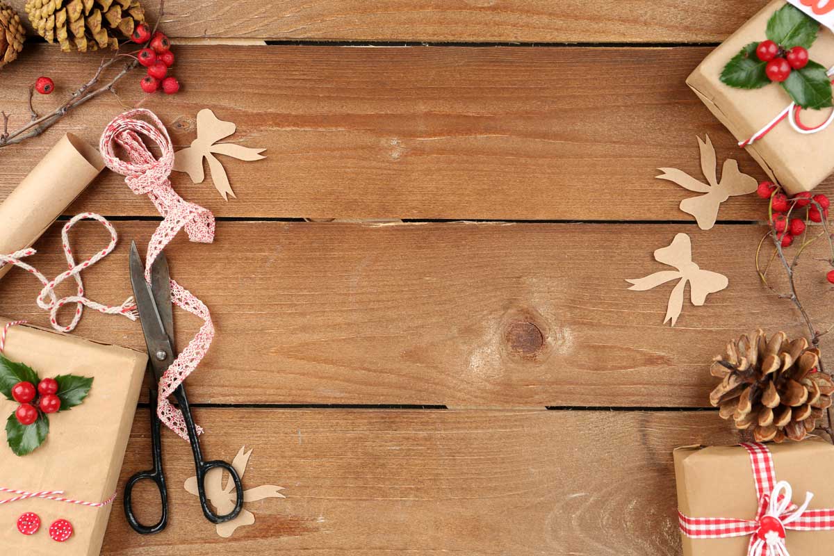 Scissors, ribbon and other crafting materials on a wooden background.