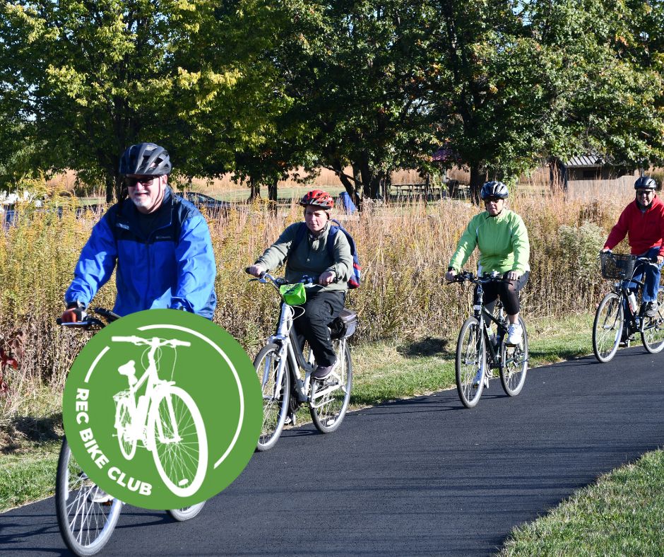 A group of four people riding bikes on a paved trail.