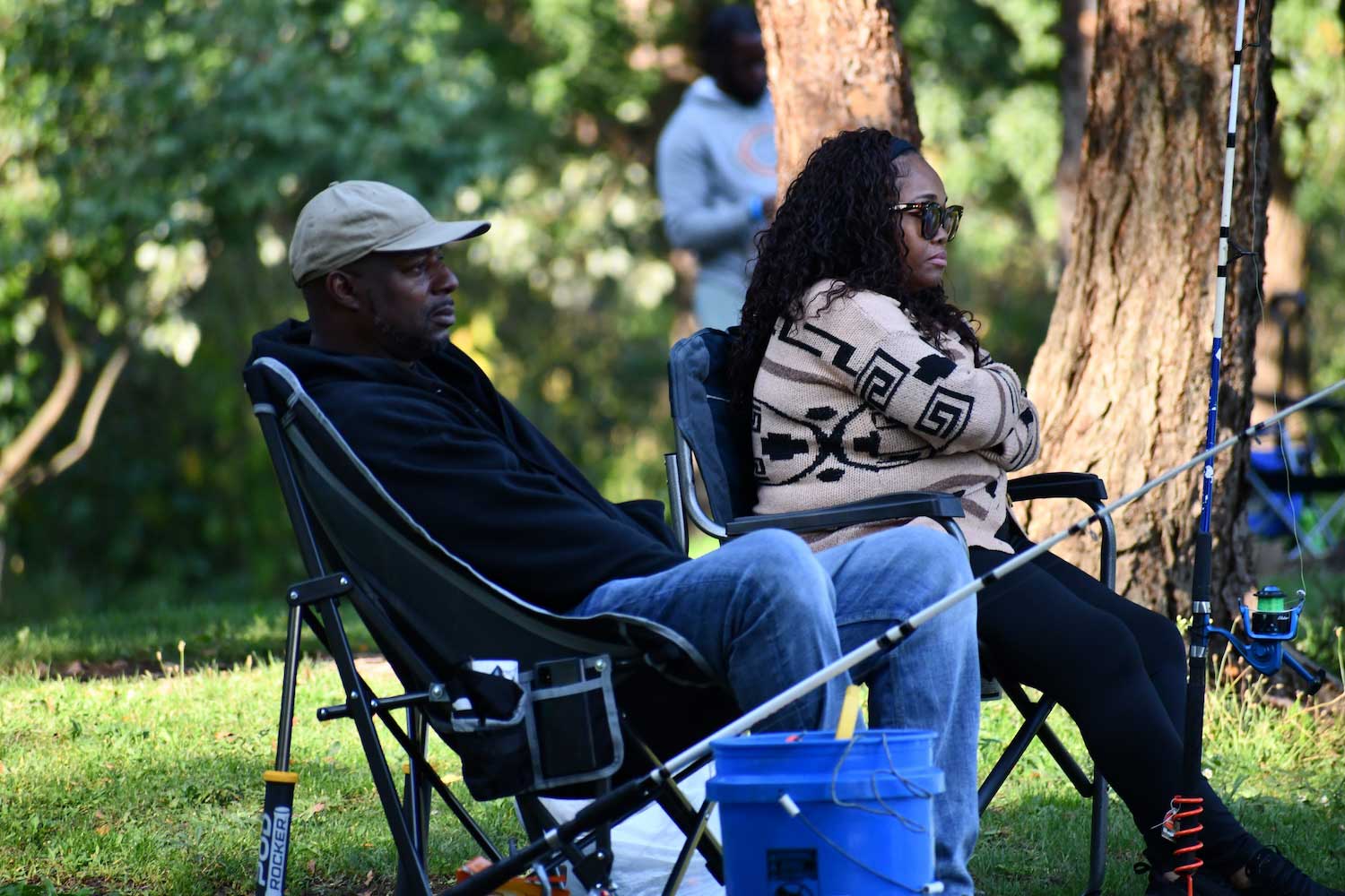 Two people sitting in chair while fishing along a shoreline