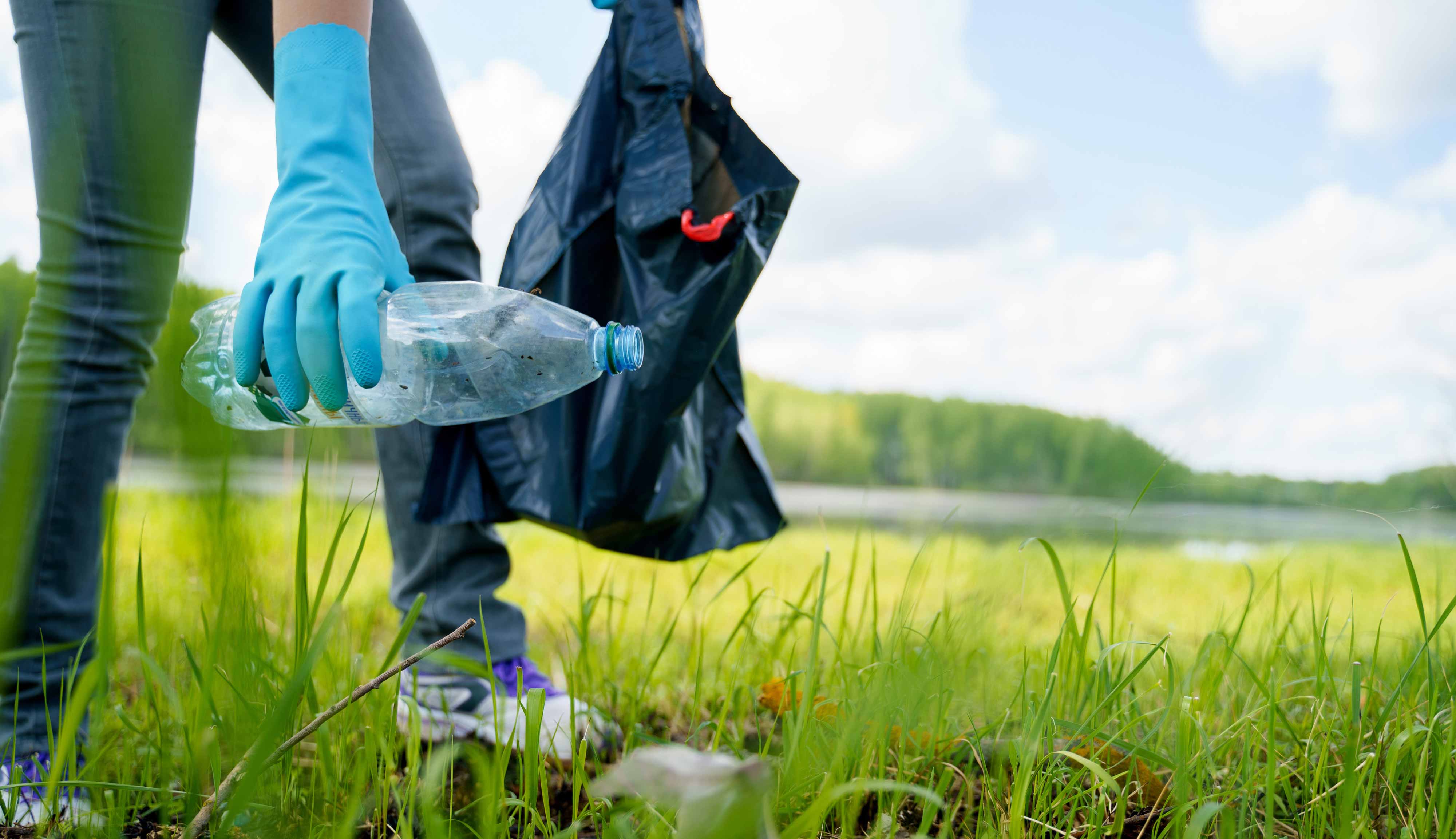 A person with a trash bag picking up litter.