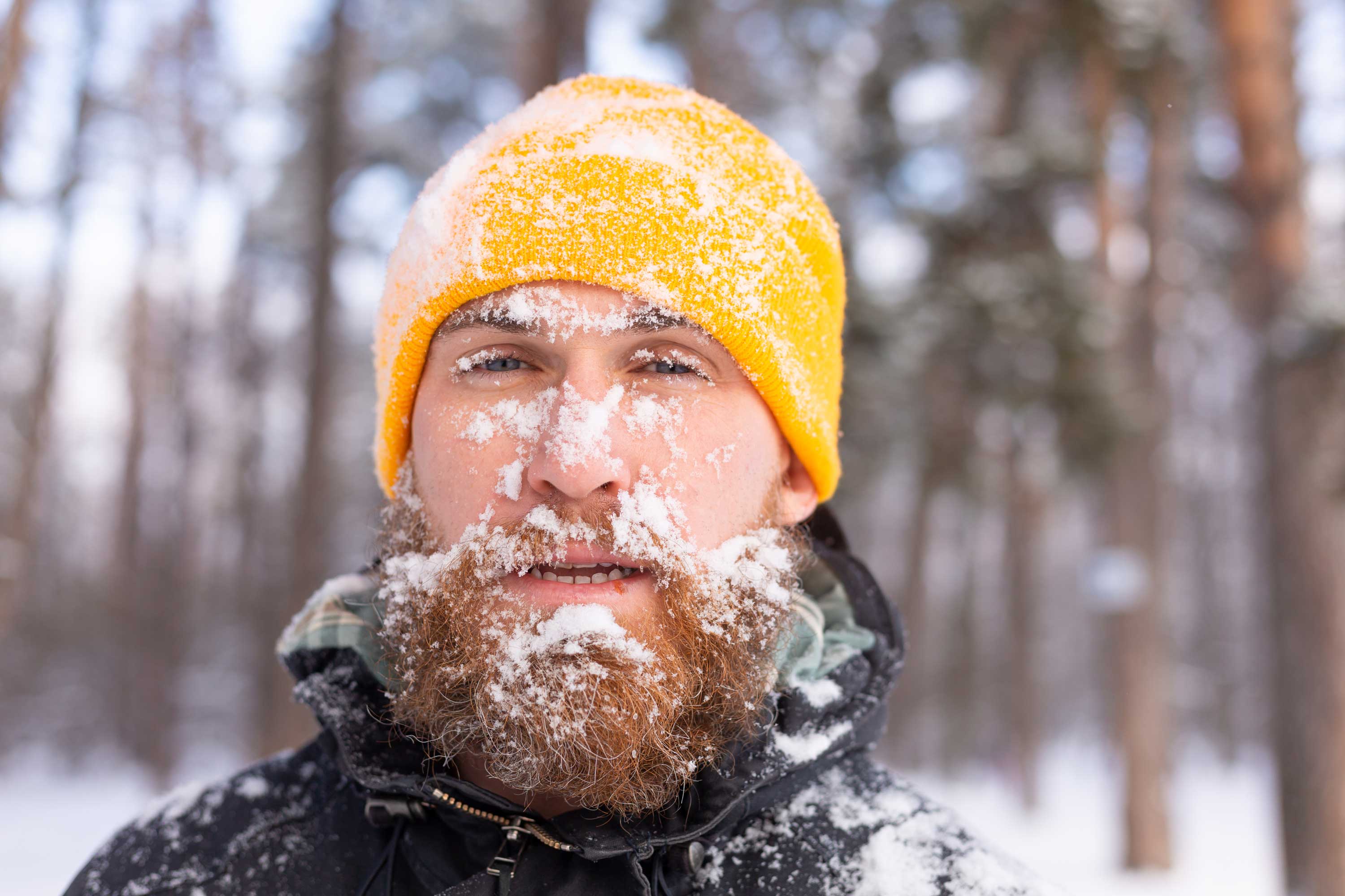 A cold man covered in snow in the woods.