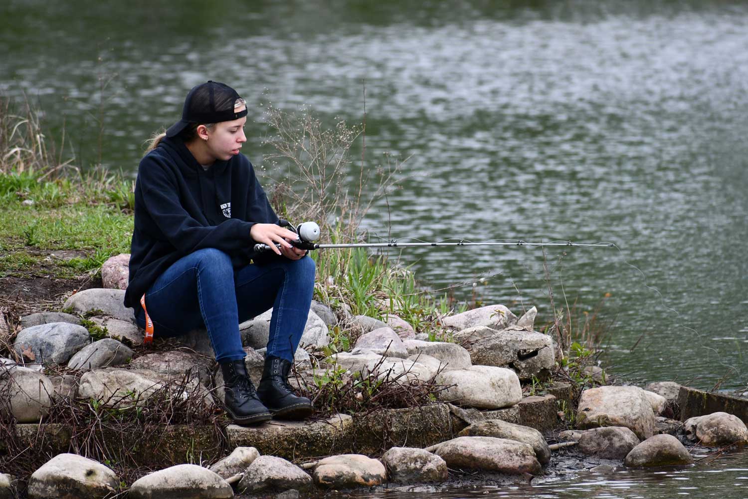 Person sitting near water while fishing.