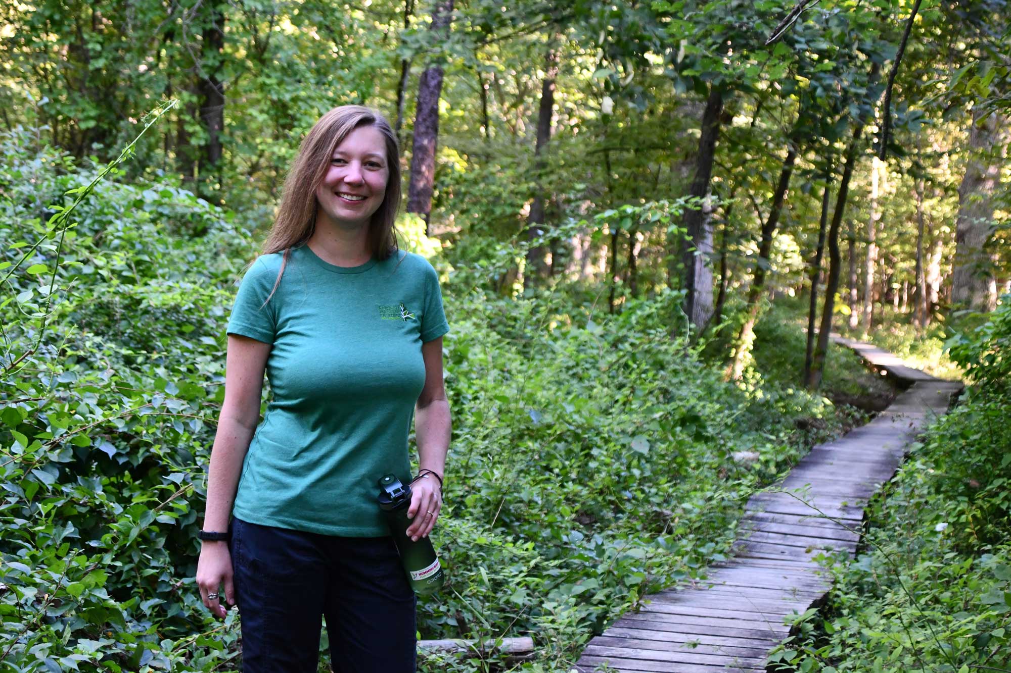 A woman stands along a boardwalk.