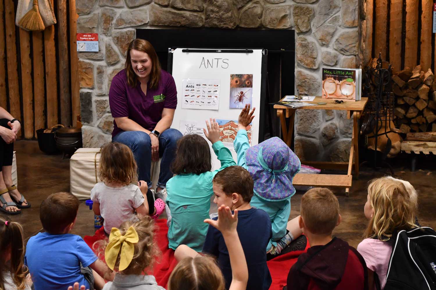 A person sitting in front of a group of kids on the floor ready to learn.
