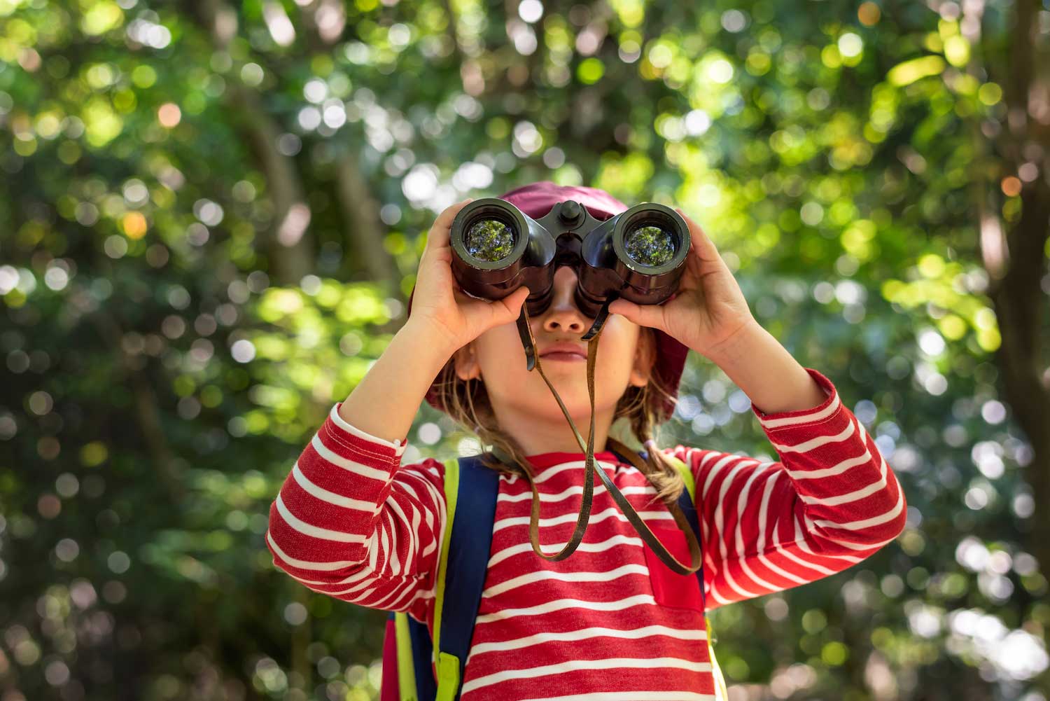 A child using binoculars to look at something in the distance.