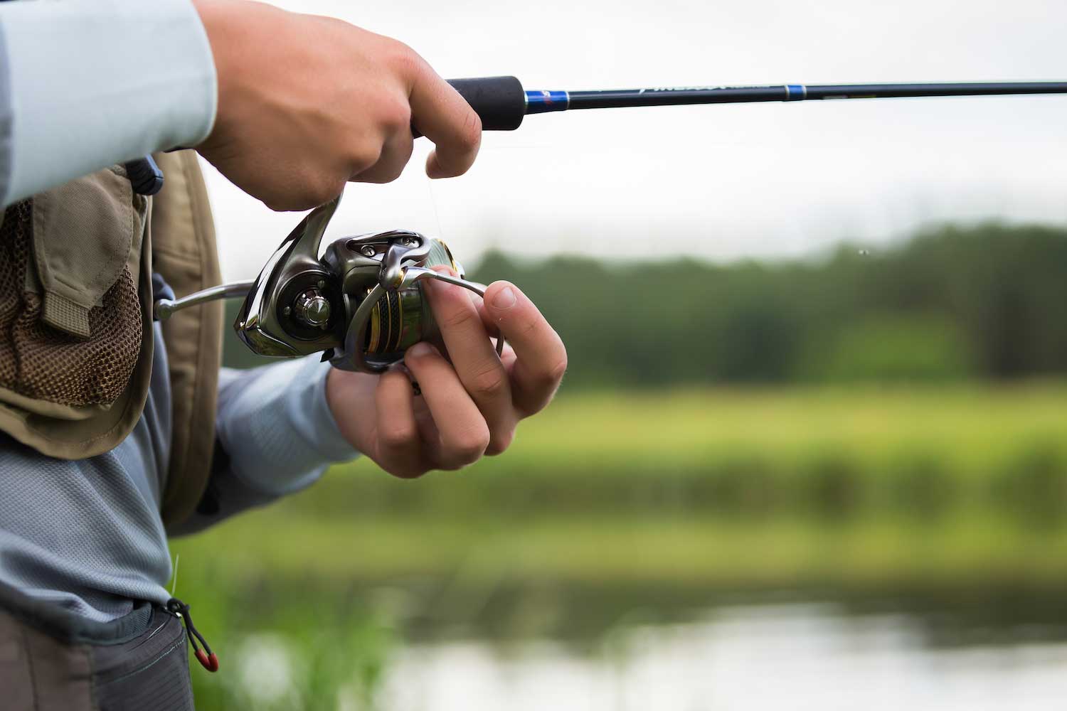 A closeup of a person's hands holding a fishing rod and reel.