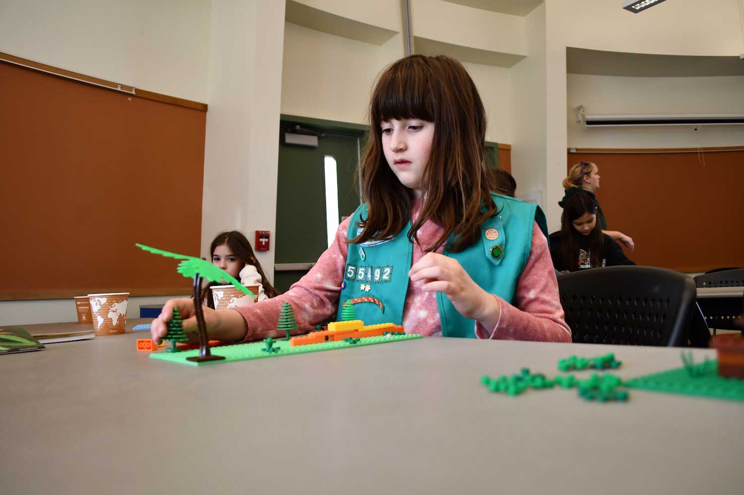 A child sitting at a table indoors building with LEGO.
