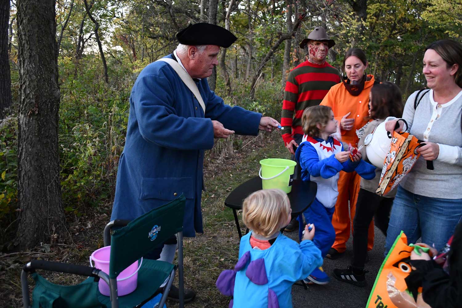 A group of people in costume on a trail. The group includes kids and adults.