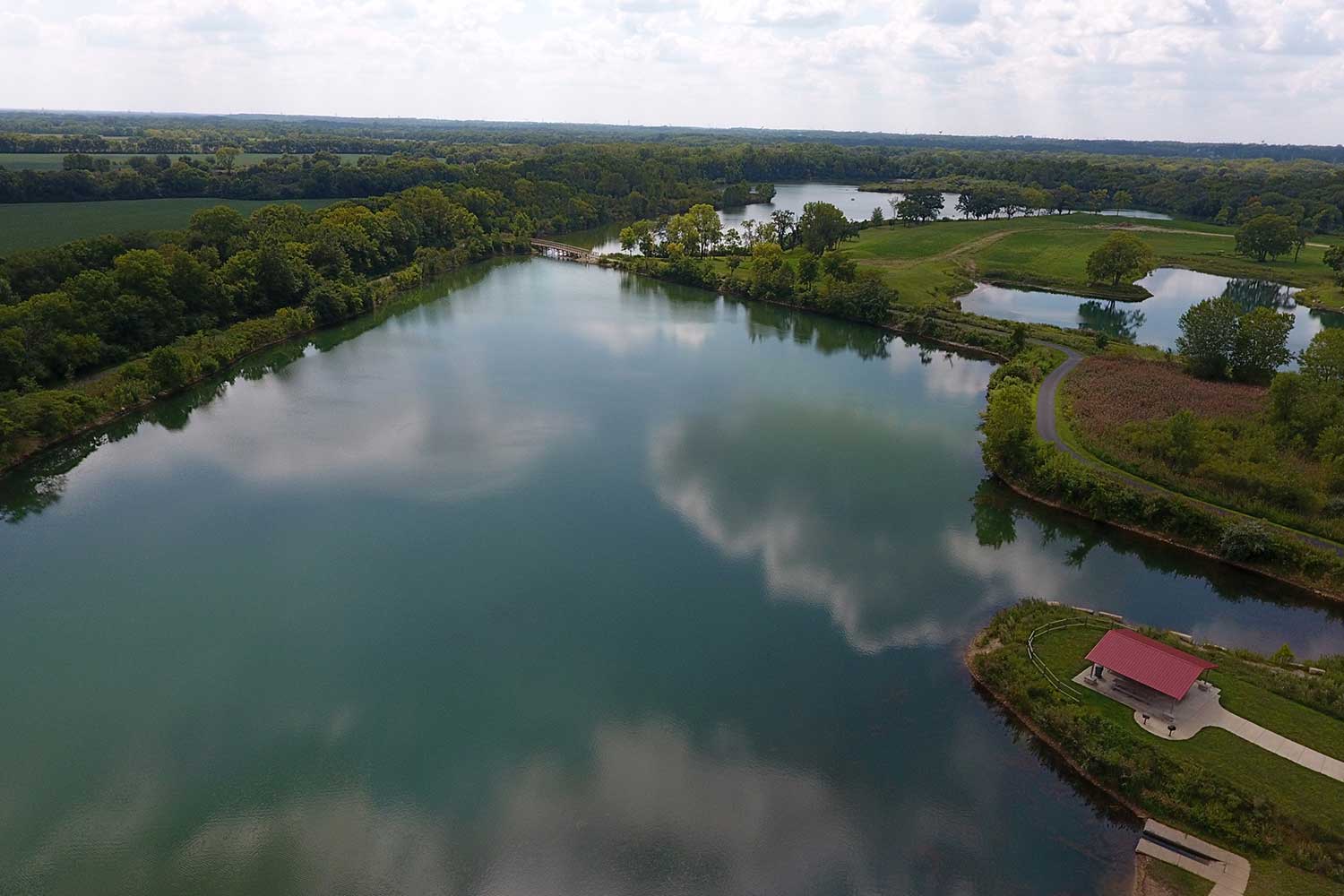 An aerial view of a lake surrounded by grasses and trees.