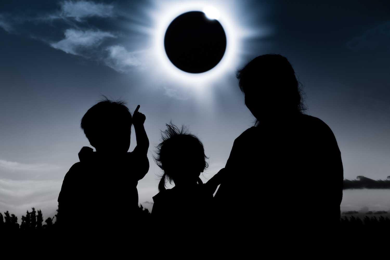 An adult and two children looking up at a total solar eclipse