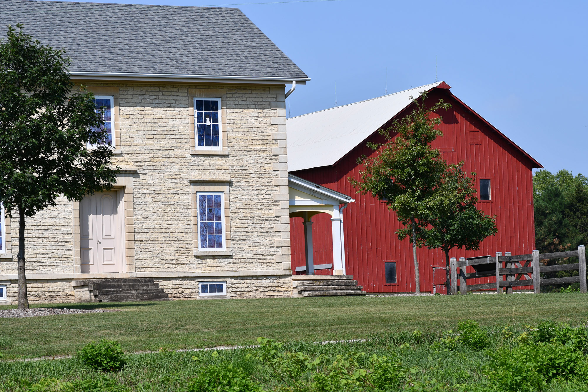 A view of a limestone house and red barn.