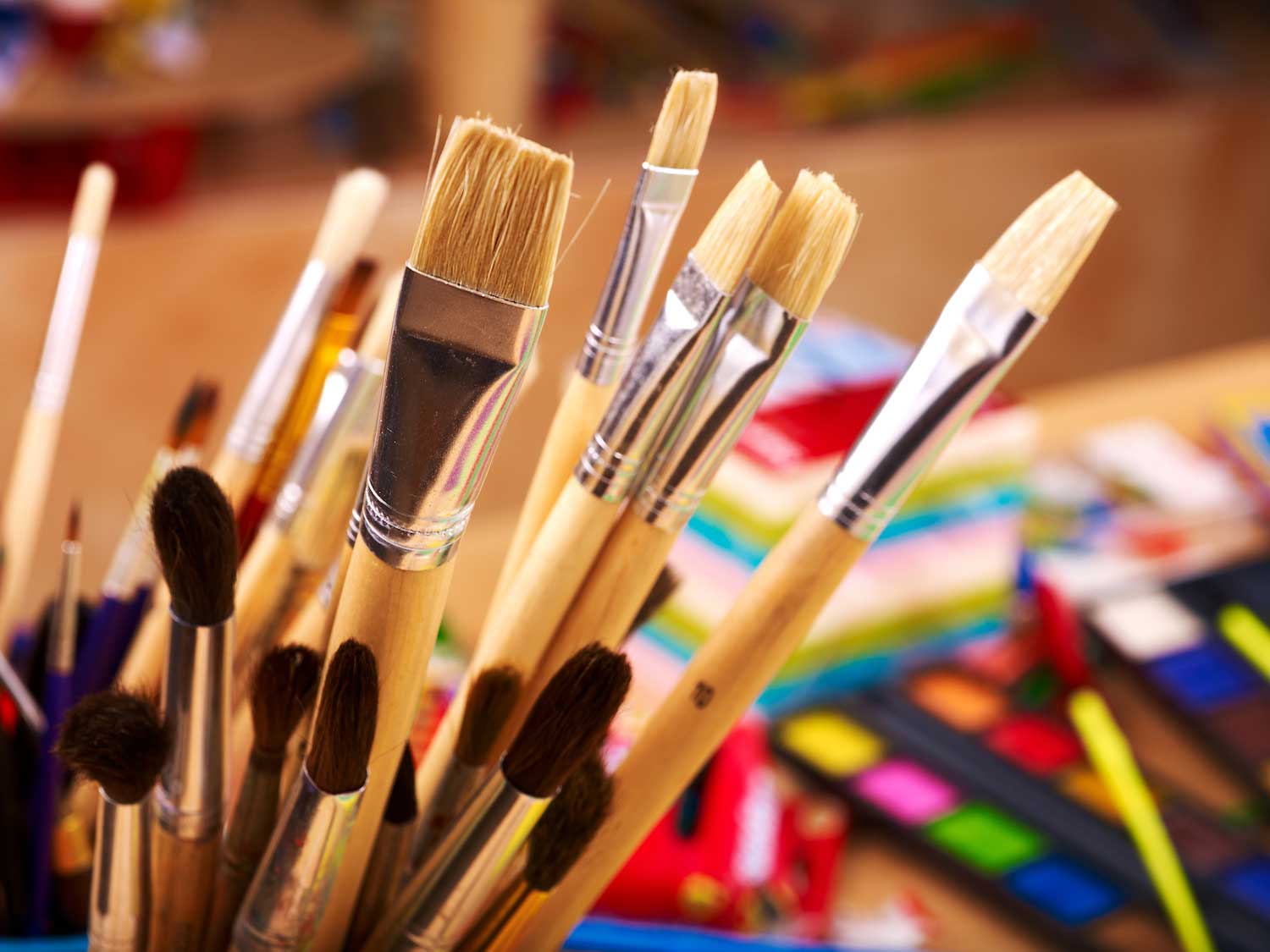 A collection of paint brushes upright in a container.