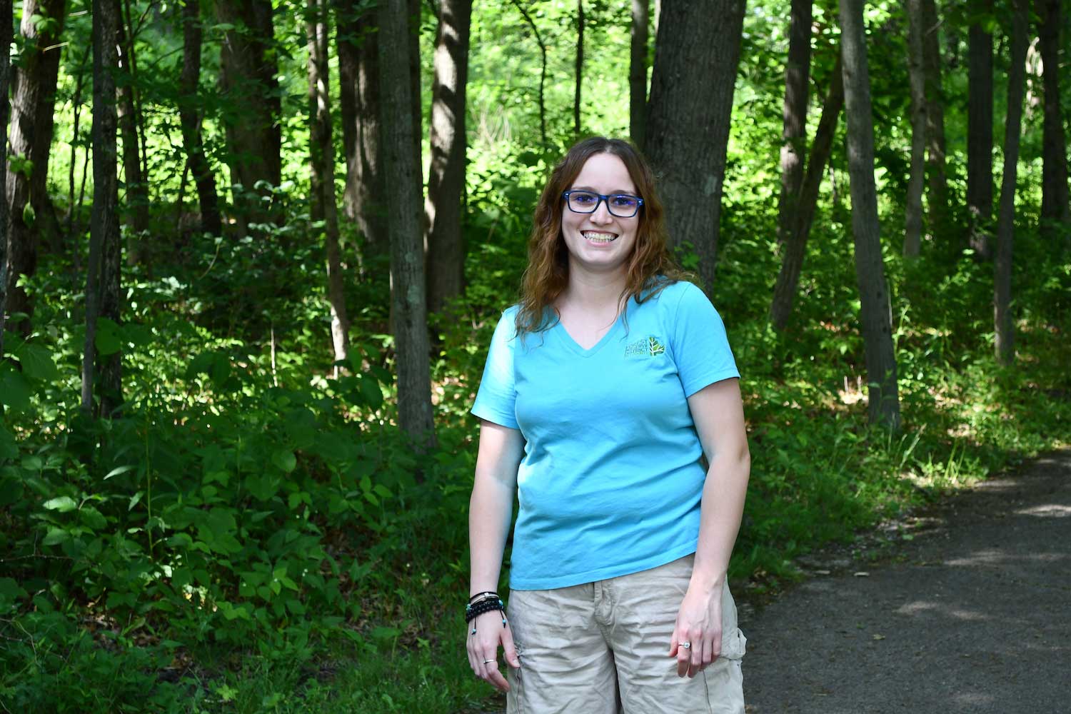 A woman standing on a path in a forest.