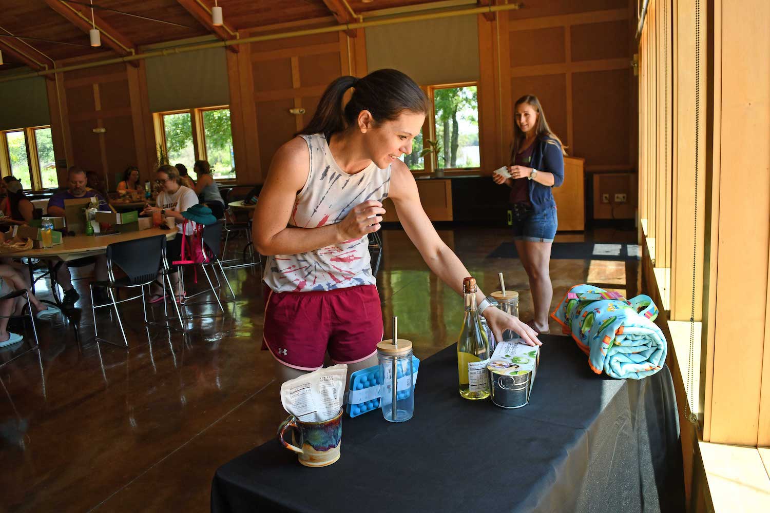 A person looking over a table full of raffle prizes while another person looks on in the background.