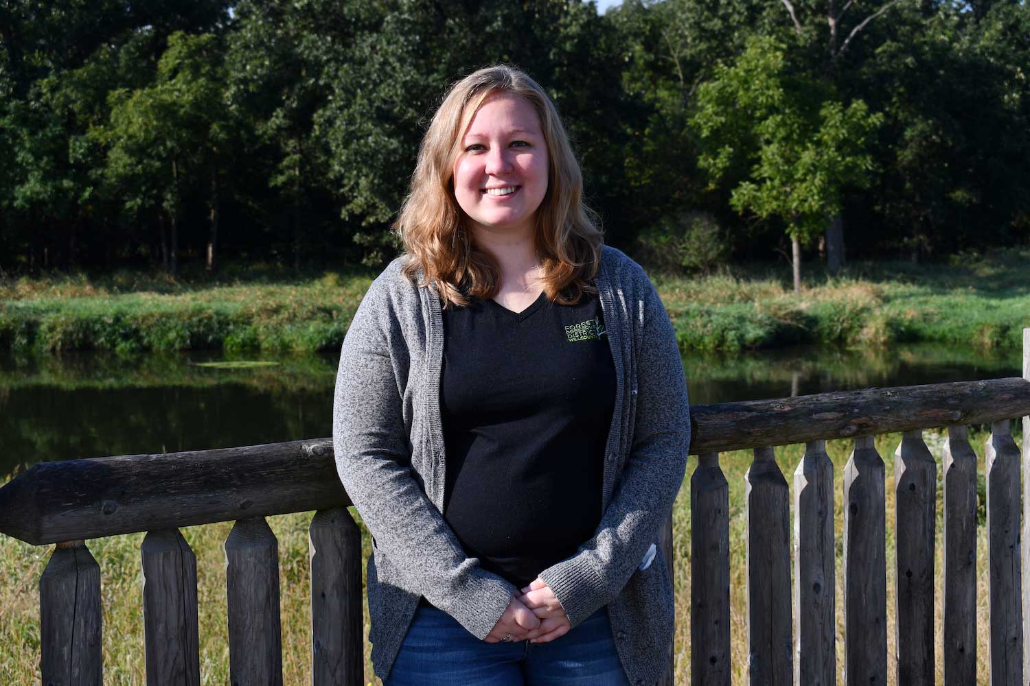 A person standing on a wooden bridge over water.