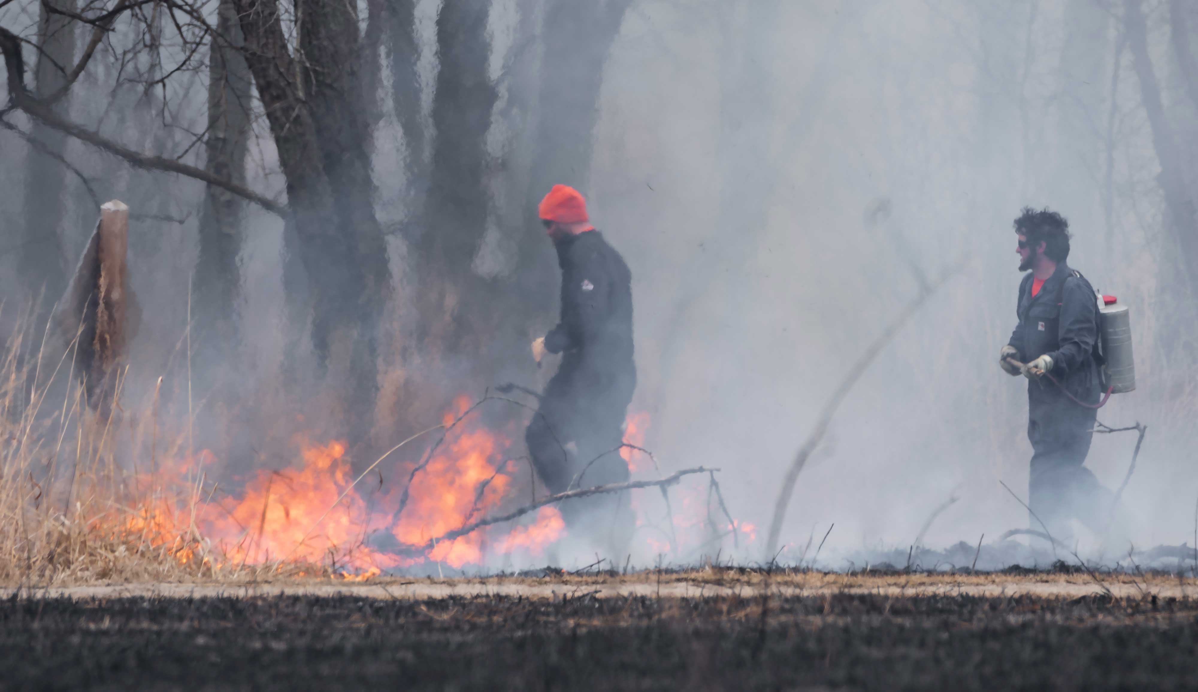 Two men participating in a controlled burn.