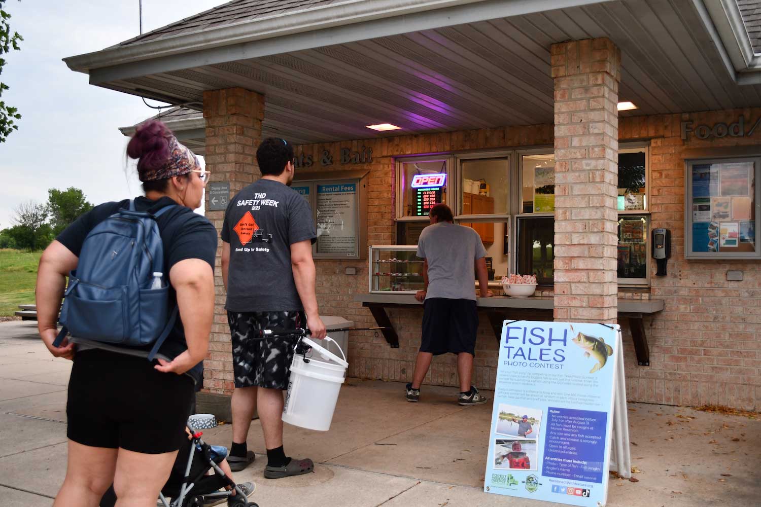 People standing in line at a concession stand at dusk.