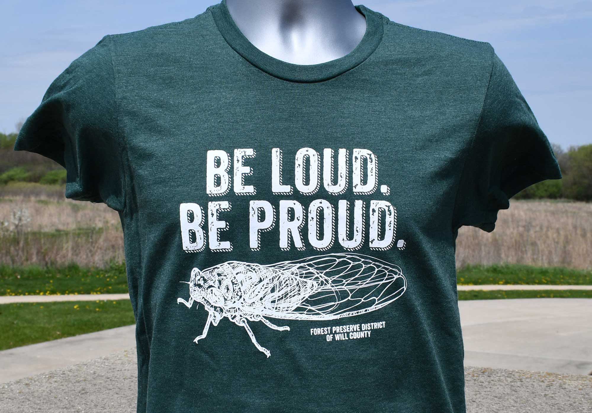 Image of a green shirt featuring a cicada and be loud be proud wording