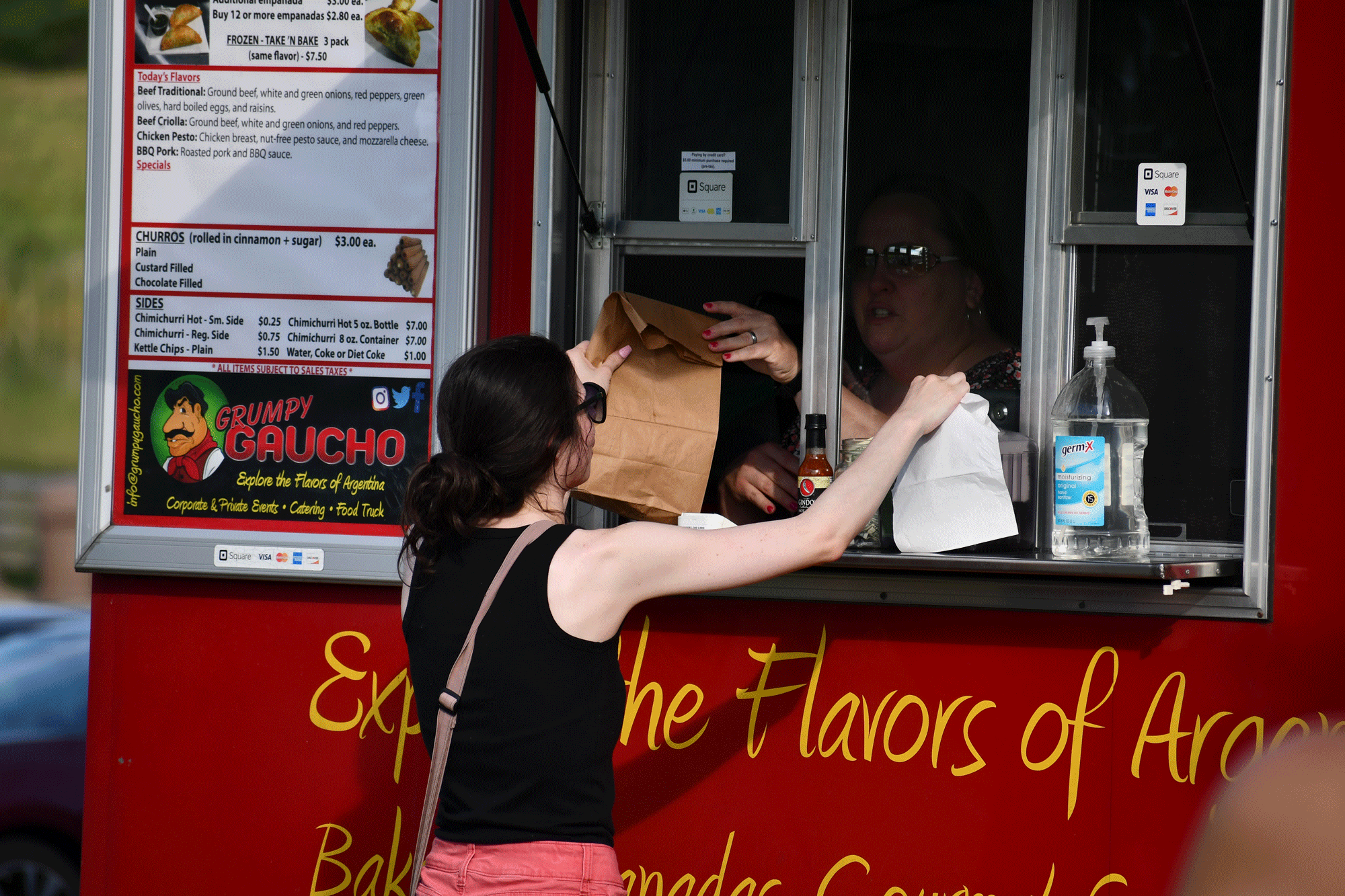 A women receiving her food from the window of a food truck.