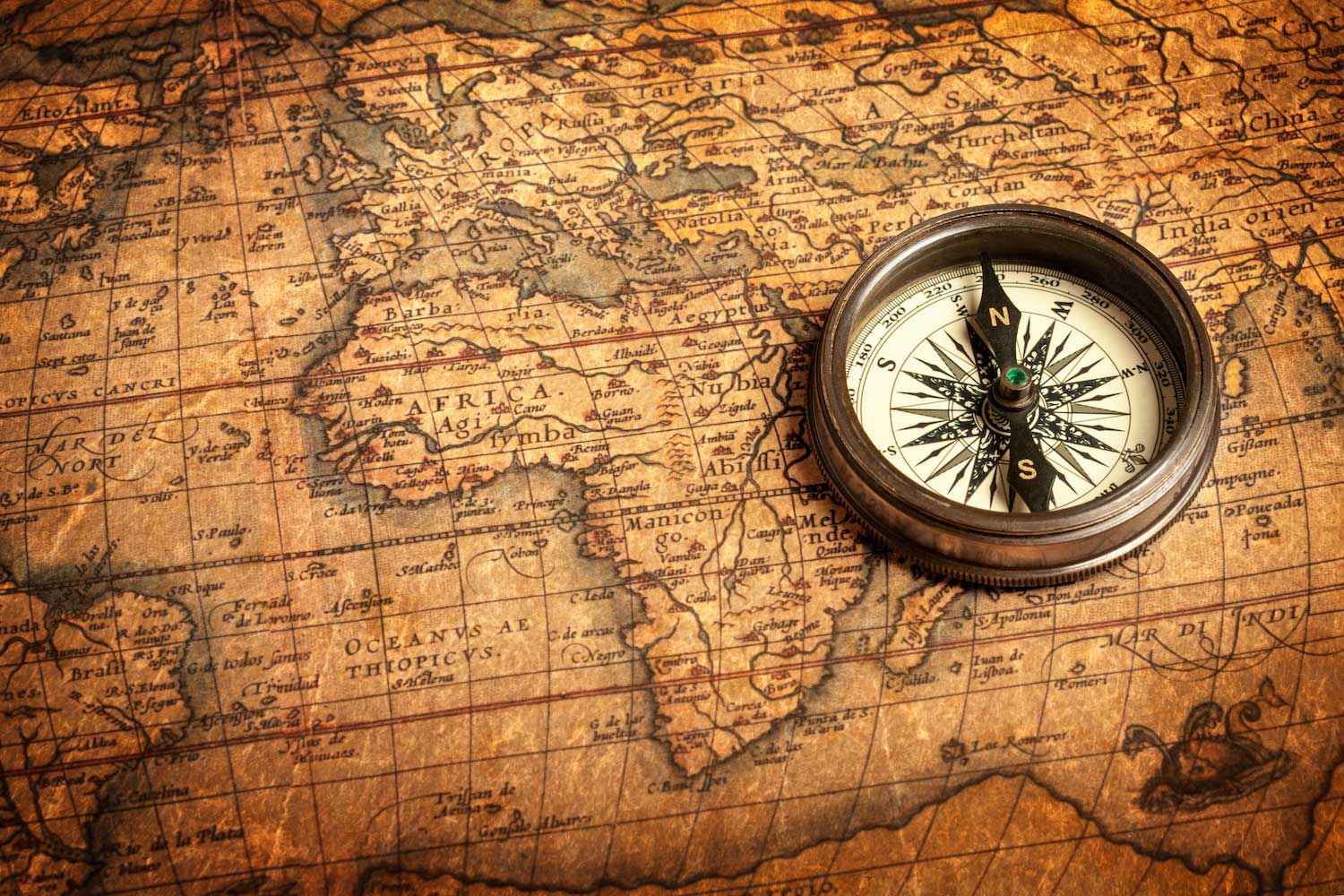 A compass sitting on a weather world map.