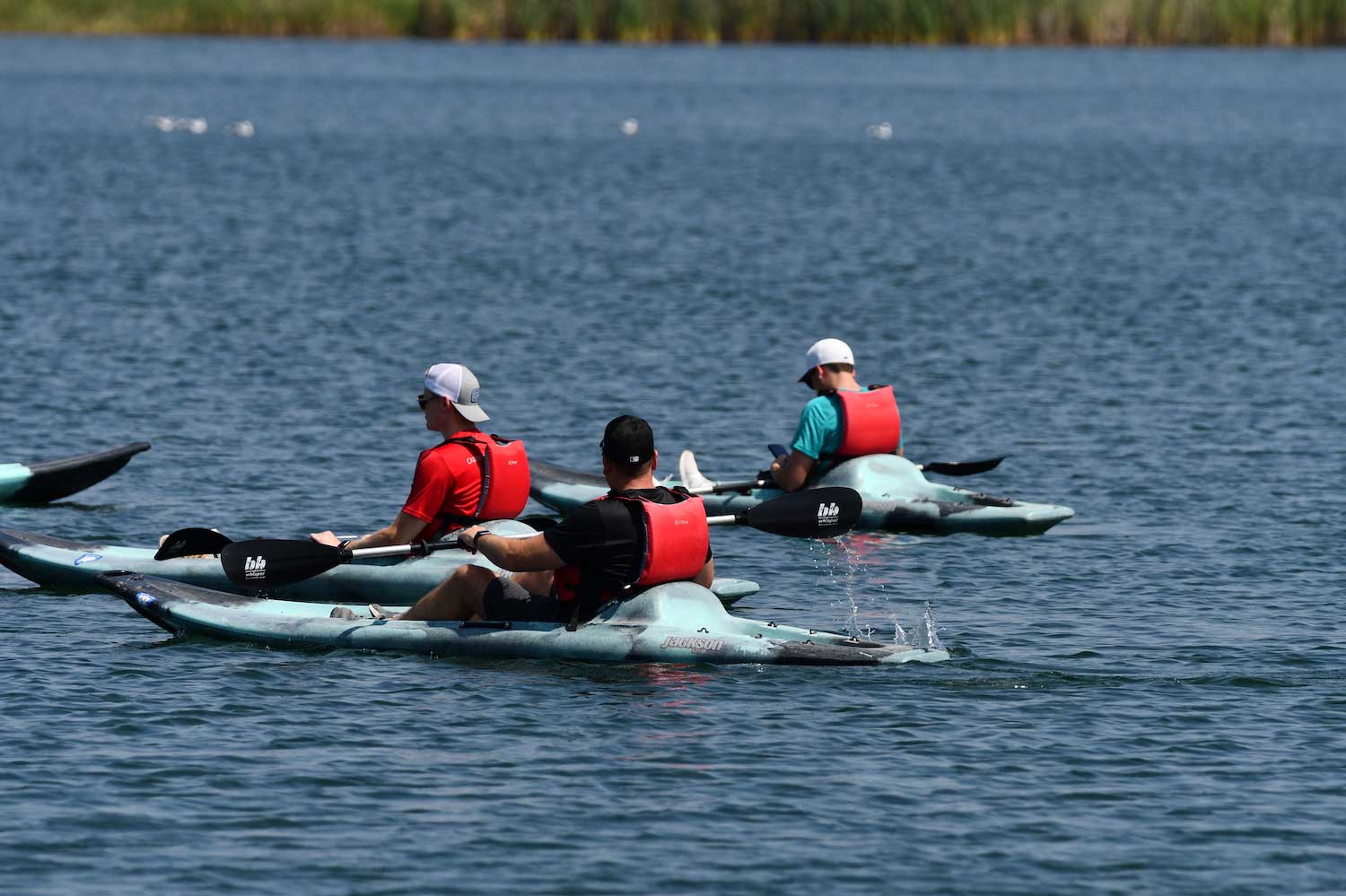 Three people on kayaks in a lake.
