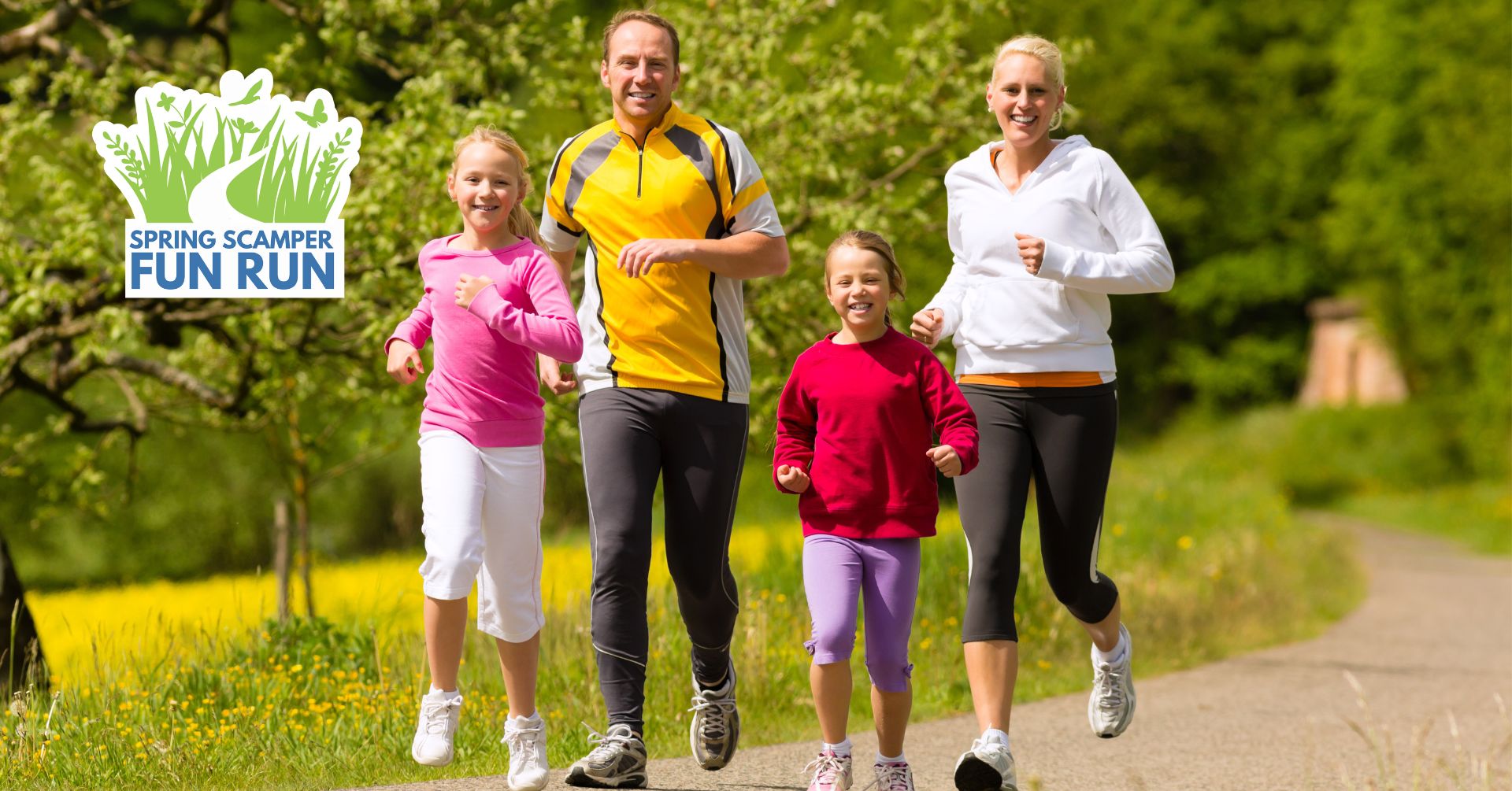 Two adults and two children running along a trail with trees in the background.